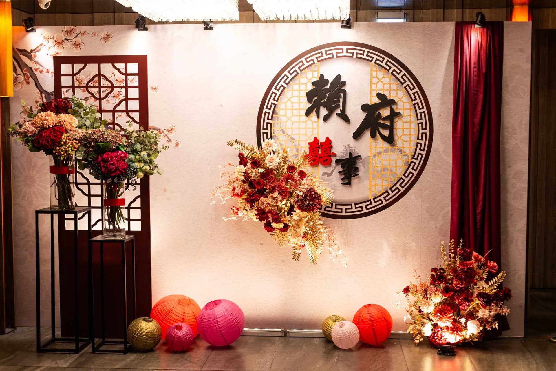 中式婚禮佈景，紅色雙囍字、花藝、燈籠，溫暖喜悅。