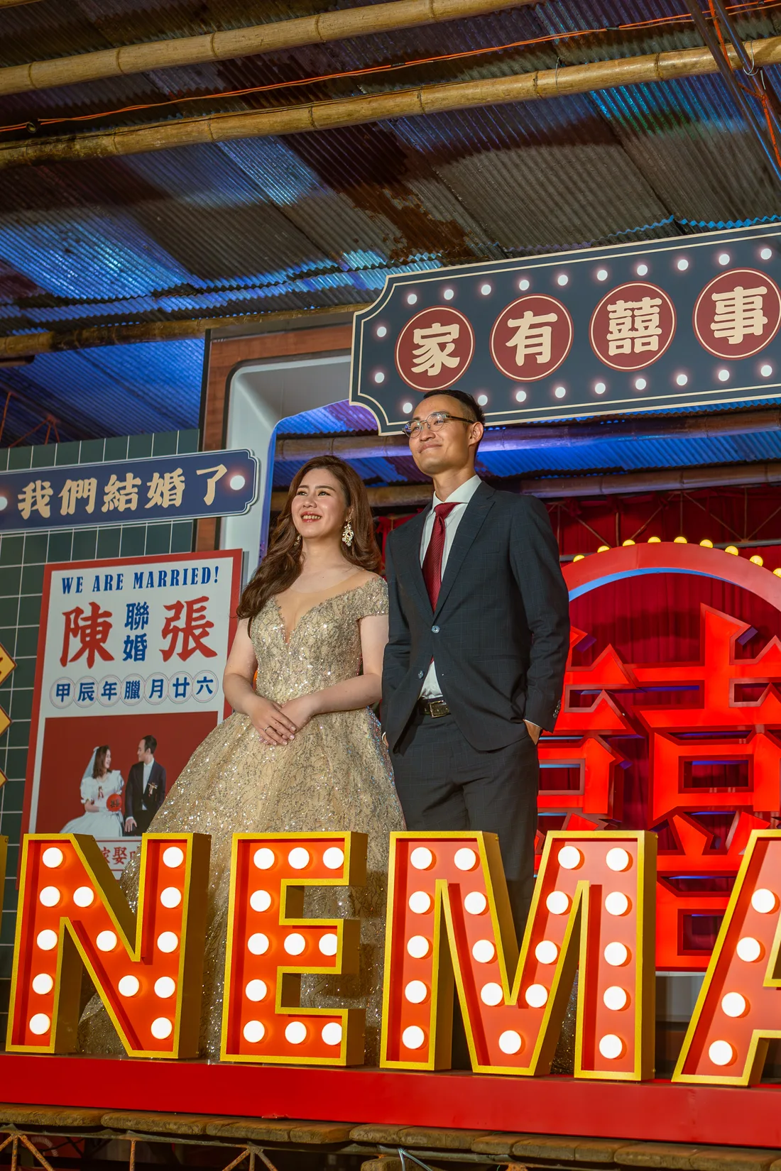 新人站在港風復古電視主題婚禮背板前，背景有家有囍事與 WE ARE MARRIED 字樣。